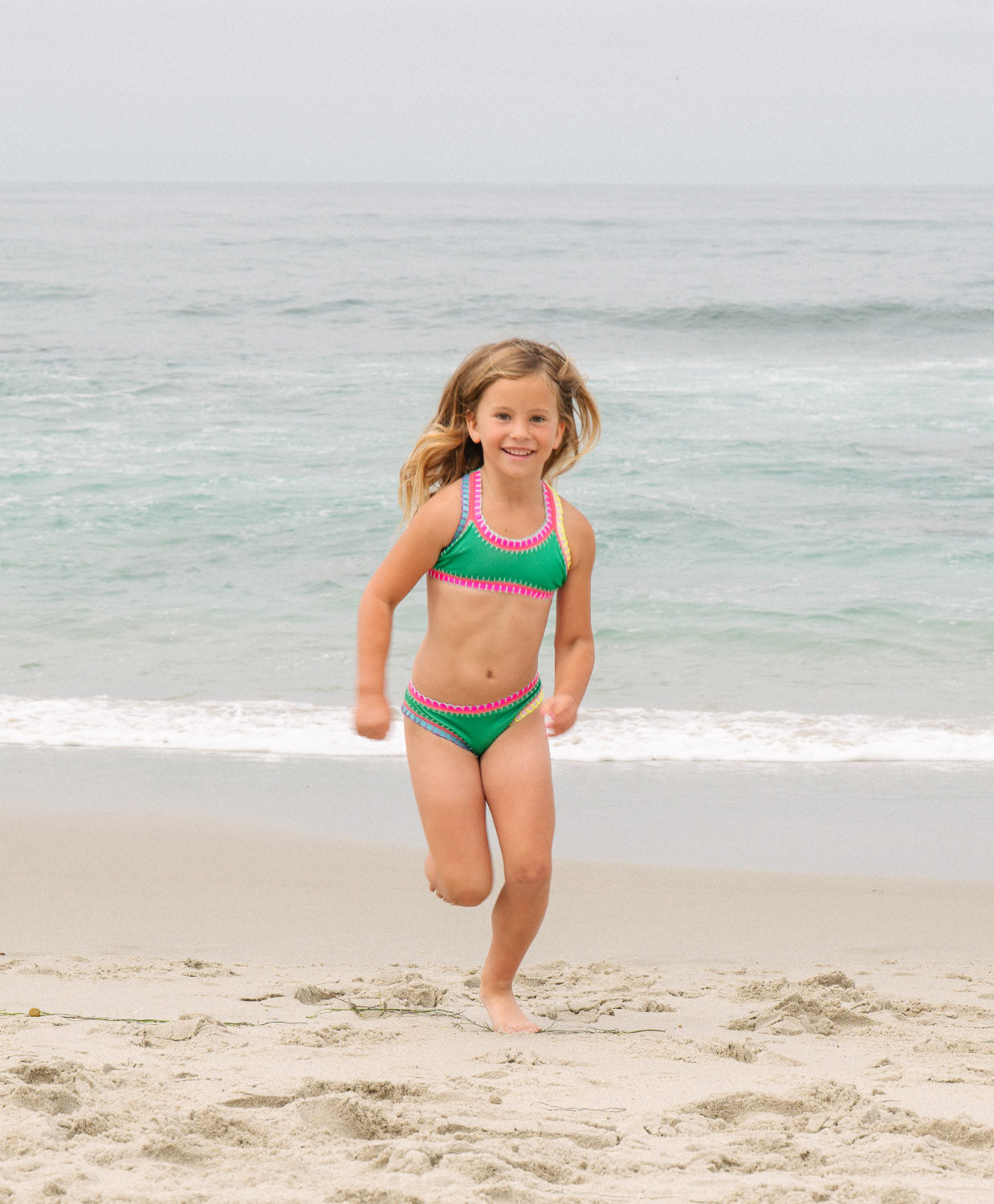 Meisje in groene PQ Swim bikini op het strand