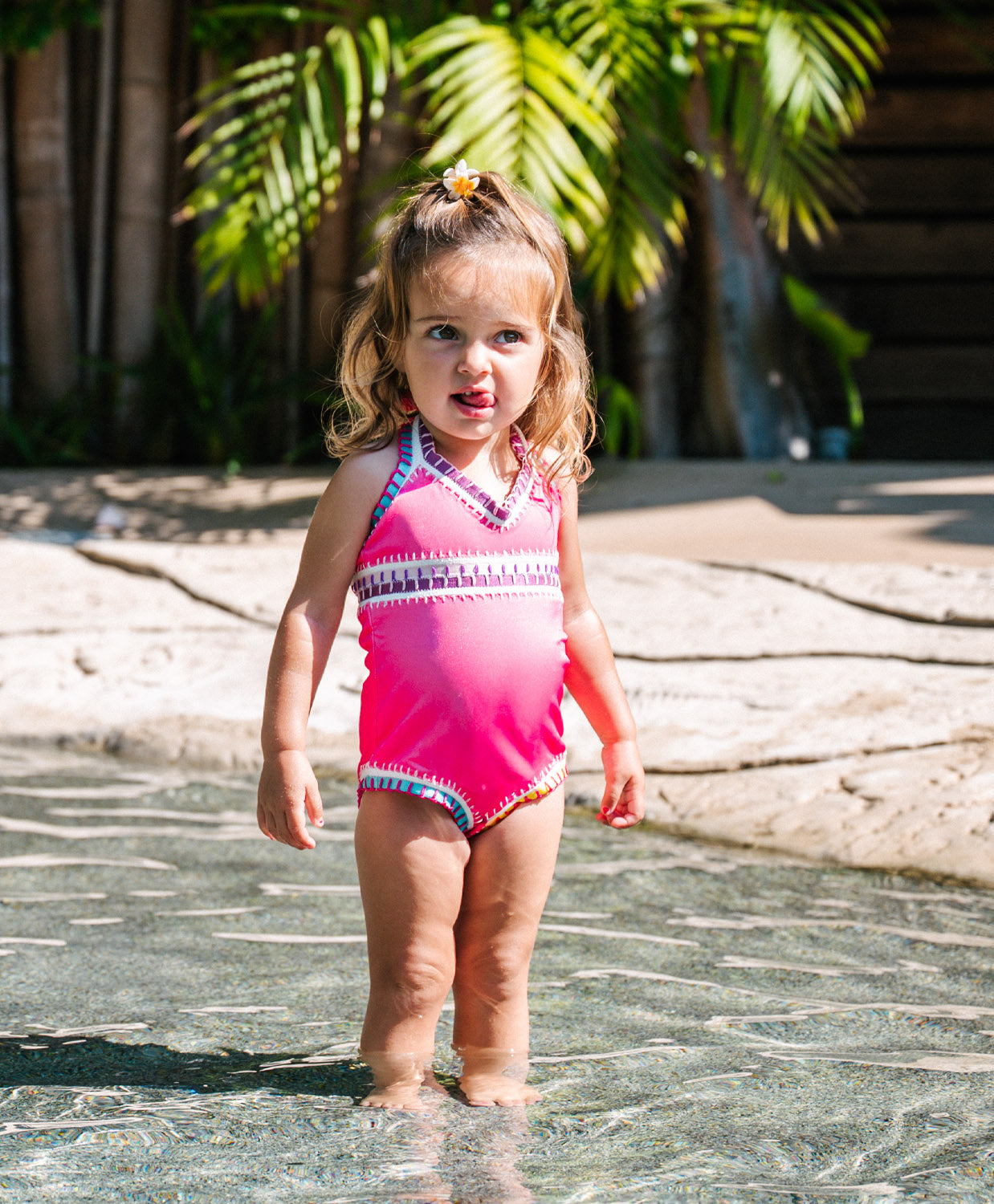 Meisje in hot pink PQ Swim badpak met regenboog borduursel